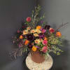 Mixed bouquet of orange, pink, and dark purple flowers in a terracotta vase