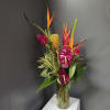 Tropical arrangement with red anthuriums and orange heliconia in a glass vase
