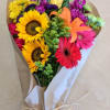 Bouquet of sunflowers, gerbera daisies, and mixed blooms wrapped in paper