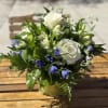 White roses and blue flowers arranged in a glass vase