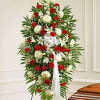 Tall standing spray of red and white flowers with a white ribbon on an easel