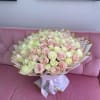 Large bouquet of pale pink and cream roses wrapped in white paper with gold trim