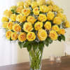 Yellow roses arranged in a clear glass vase with baby's breath