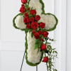 Cross-shaped floral tribute with red roses and white flowers on an easel
