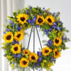 Sunflower wreath with blue flowers on a black stand