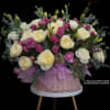 Pink and cream roses arranged in a wicker basket with a lavender ribbon.