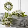 White floral funeral arrangements around a silver casket