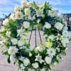 White floral wreath on a black stand outdoors