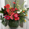 Large mixed flower arrangement in a glass vase with pink and red blooms