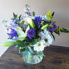 Purple and white mixed bouquet in a clear glass vase