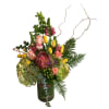 Mixed bouquet with pink roses, yellow tulips, and a protea in a glass vase