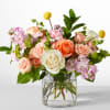 Bouquet of peach, white, and pink roses in a clear glass vase