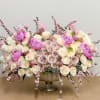 Large pastel floral arrangement in a pedestal vase with pink and cream roses