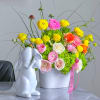 Colorful flower arrangement in a white vase beside a white rabbit figurine