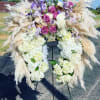 Large floral funeral spray with white hydrangeas, purple roses, and pampas grass