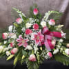 Pink and white floral spray with lilies, roses, and ribbon