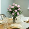 Lavender rose bouquet in a clear glass vase on a set dining table