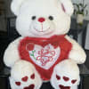 White teddy bear holding a red heart pillow with "Love You" text