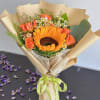 Bouquet with a sunflower, orange roses, and small white daisies in kraft paper