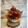 Autumn floral arrangement in a white pumpkin container with red roses and fall leaves