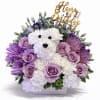 Birthday flower arrangement with a white carnation dog, lavender roses, and purple mums in a white container.