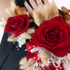 Red rose corsage with beige dried accents and ribbon on a wrist