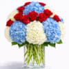 Red roses and blue-white hydrangeas in a clear glass vase