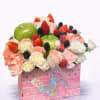 Fruit and flower arrangement in a pink gift box with a butterfly ribbon