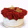 Round box of red roses topped with gold butterfly decorations