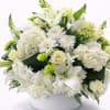 Low round arrangement of white lilies, roses, hydrangeas and green mums in a white bowl.