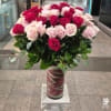 Bouquet of pink and red roses in a tall glass vase