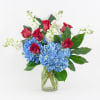 Red roses and blue hydrangeas in a clear glass vase