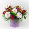 Mixed bouquet of pink and white flowers in a lavender hat box