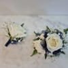 Two white rose boutonnieres with navy ribbon accents