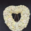 Heart-shaped white floral wreath on a stand