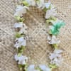 White and green flower lei on a woven mat