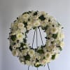 White floral wreath on a black stand