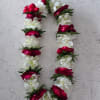 Full double white orchid lei with evenly spaced red rose petal clusters
