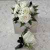 A cluster of pure white roses tied with dark ribbon makes an