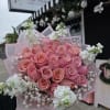 A rounded cluster of soft pink roses forms the heart of this