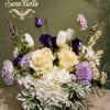 Bouquet of cream roses, white hydrangea, and purple blooms in a low vase