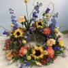 Bright mixed wildflowers including sunflowers, roses, dahlias and blue delphinium, arranged with
