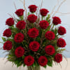 Velvety, deep red roses with textured greenery in a tall clear vase