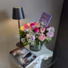  A vase arrangement of roses, light, book and candy. It's a