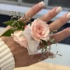 Small blush rose corsage with ribbon on a hand