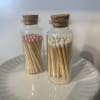 Two glass bottles filled with wooden matches, one with pink tips and one with white tips