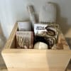 Gift basket with soaps, candles, and chocolates in a wooden crate