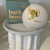 Bath bomb on a ceramic pedestal with its box behind it