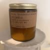 Amber jar candle with a gold lid on a white pedestal
