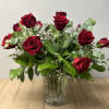 Red roses arranged in a clear glass vase with greenery